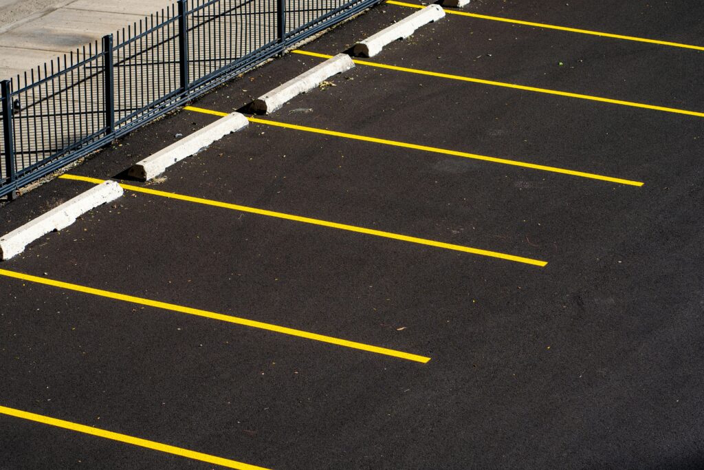 Top view of an empty parking lot with yellow lines and a metal fence, perfect for urban scenes.